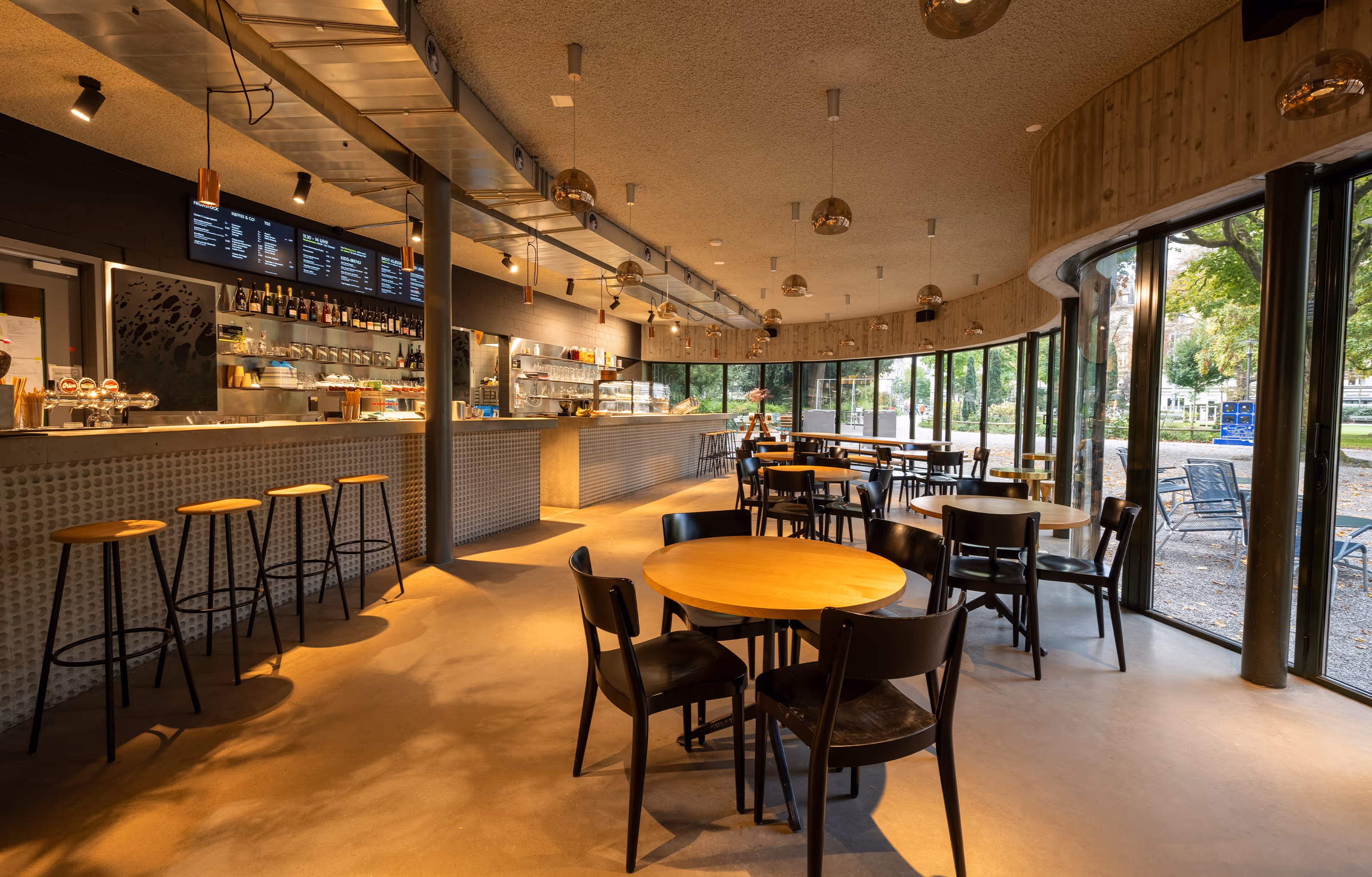 Gastraum mit Bar, Holztischen und Panoramaverglasung zum Park im Brot Bistro Bar Zürich